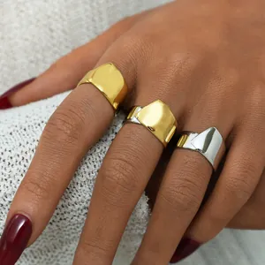 Anelli larghi geometrici minimalisti in finitura oro e argento sulla mano della modella