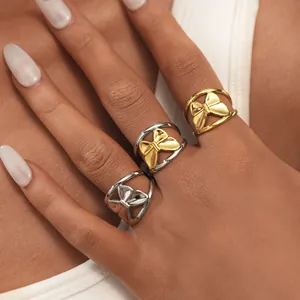 Detail view of bow-knot titanium steel rings in gold and silver on model's hand