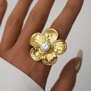 Gros plan sur la bague fleur dorée avec texture striée et pierre centrale brillante