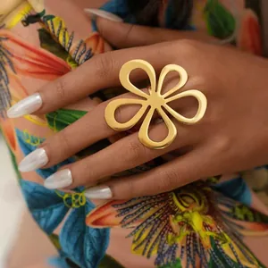 Gros plan d'une grande bague fleur dorée avec pétales en cœur sur la main du mannequin