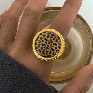 Close-up of chunky gold rope-edged ring featuring a bold leopard print center on a finger