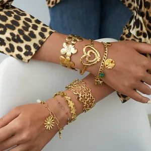 Detail of layered gold flower cuffs and heart bracelets worn with leopard print outfits