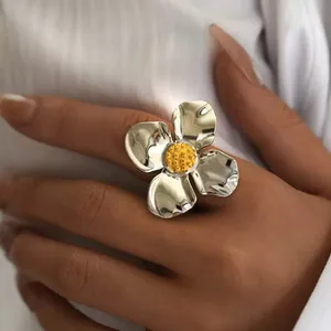 Vue détaillée d'une grande bague fleur argentée avec cœur jaune portée à la main