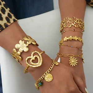 Close-up of stacked gold floral bracelets with hollow patterns and bead charms on wrist
