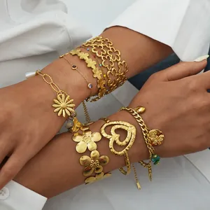 Detail shot of gold cutout floral bangles and gemstone bracelets worn for styling
