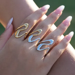 Close-up of wavy liquid metal rings in gold and silver finishes on a model hand
