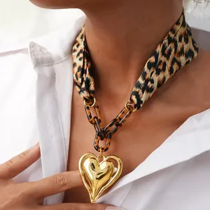 Close-up of leopard print silk scarf necklace with large golden metal heart pendant