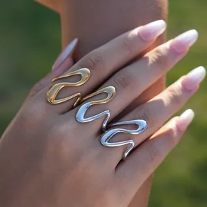 Close-up of polished gold and silver wavy stackable rings worn on a hand in natural light