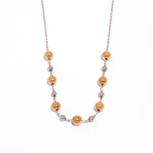 Vintage style beaded necklace with gold and silver stainless steel balls on white surface