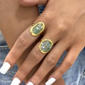 Close-up of dual gold rings with irregular oval green stone inlays on a hand