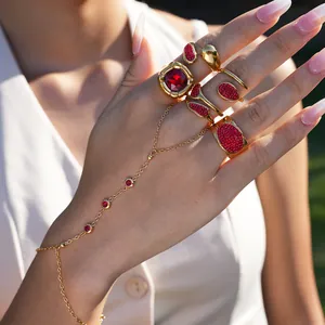 Detail of luxury gold hand chain and rings set with sparkling red crystals on model