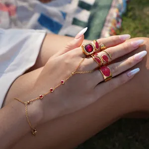 Luxury gold ring set and finger bracelet with red zircon gemstones on outdoor background