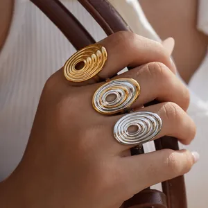 Three geometric spiral titanium steel rings in gold and silver on a leather handle
