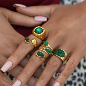 Gold plated ring set with green emerald crystals shown on a model's hand in luxury style