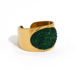 Polished gold cuff bracelet featuring an oval cluster of inlaid green rhinestones