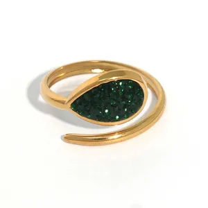 Macro detail of gold-plated drop-shaped ring featuring pavé green cubic zirconia crystals