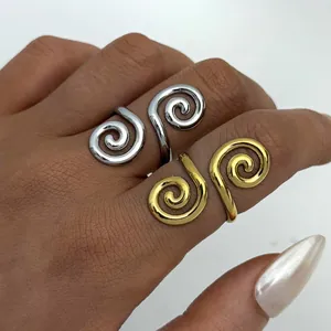 Spiralförmige, hohle offene Ringe in Gold und Silber auf einer Hand präsentiert