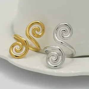 Elegante goldene und silberne Spiralringe mit minimalistischem Wirbeldesign auf Keramik