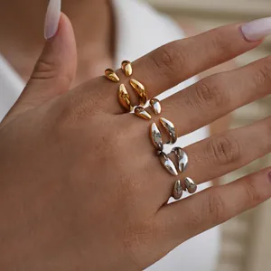 Primer plano de cuatro anillos orgánicos en acabados oro y plata en los dedos