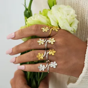 Detailed close-up of double flower open rings in gold and silver finishes on a model's hand