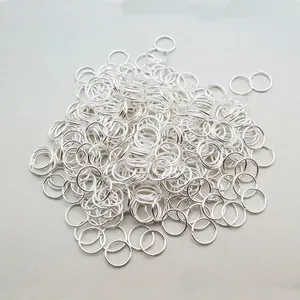 Close-up of silver metal jump rings for DIY jewelry making on a light grey background