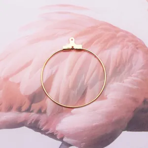 Gros plan sur le connecteur de boucle d'oreille doré rond DIY sur fond de plumes douces