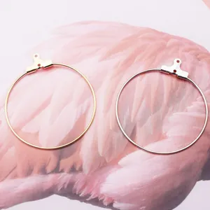 Anneaux de boucles d'oreilles ronds DIY en or et argent sur texture de plumes roses
