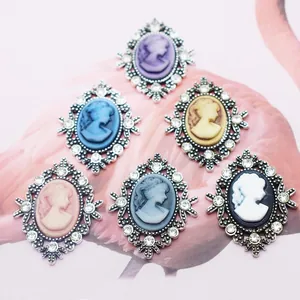 Vintage oval cameo charms with rhinestones in six colors on pink feather background