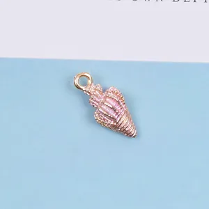 Detailaufnahme eines rosa Emaille-Muschel-Anhängers mit goldenem Metallrahmen für DIY-Schmuck