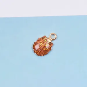 Detail eines muschelförmigen Anhängers mit goldener Basis und glitzerndem Öl-Finish