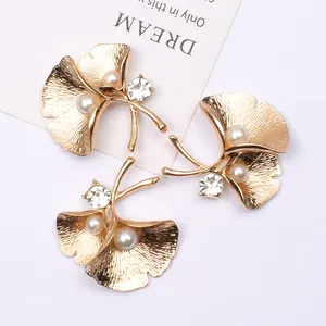 Detailaufnahme goldener Ginkgoblatt-Haarschmuck mit Perlen und Kristallen auf weißem Grund