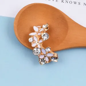 Detail der gebogenen Goldschnalle mit weißen Blüten und glänzenden Strasssteinen für DIY