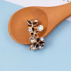 Nahaufnahme von blumenförmigem Legierungszubehör mit schwarzer Emaille und Kristallen
