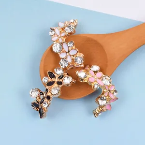 Blumiger Zahnschmuck aus Emaille mit Strass auf Goldlegierung in einem Holzlöffel