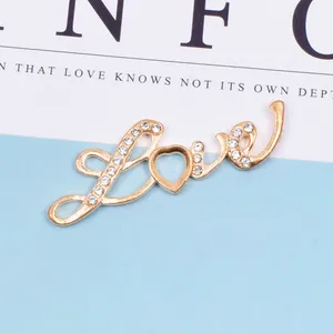 Nahaufnahme des goldenen Love-Anhängers mit glitzernden Strasssteinen und Herzform