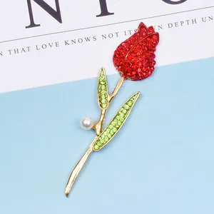 Detailaufnahme einer goldenen Tulpenbrosche mit roten Kristallen und einer weißen Perle