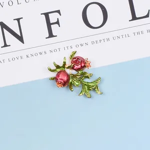 Detail einer roten Granatapfel-Emaille-Brosche mit grünen Blättern für DIY-Brautschmuck