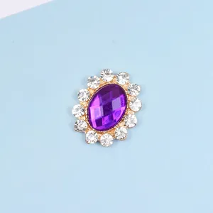 Close-up of oval purple gemstone alloy accessory with white rhinestones and gold plating