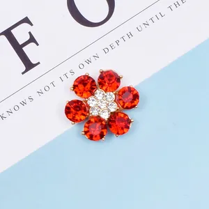 Dettaglio del ciondolo a fiore in cristallo rosso con base dorata e pietre bianche