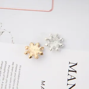 Close-up of gold and silver snowflake alloy charms with detailed radial textures for DIY