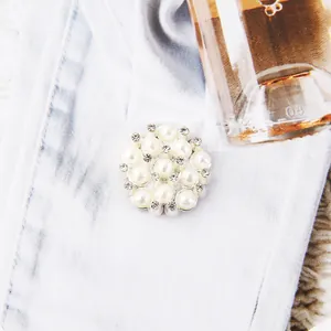 Macro detail of a silver alloy flower button featuring white pearls and clear rhinestones
