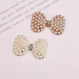 Detail of elegant bow-shaped alloy charms with white pearls and sparkling rhinestones