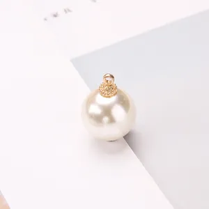 Detailed macro view of a cream pearl charm with a textured golden crown metal cap