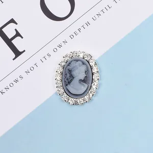 Close-up of vintage oval cameo button with white relief and crystal rhinestone border