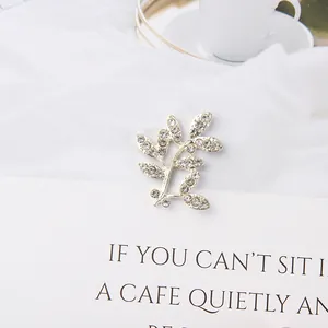 Macro shot of silver leaf-shaped brooch with inlaid sparkling rhinestones on card