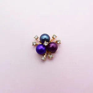 Macro detail of three-color pearls with sparkling rhinestones in golden metal setting