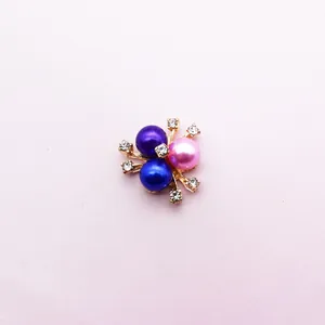 Close-up of alloy flower accessory with three colorful pearls and sparkling rhinestones