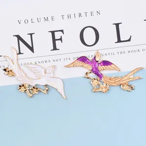 Golden bird brooches with white and purple enamel, featuring intricate floral and feather details