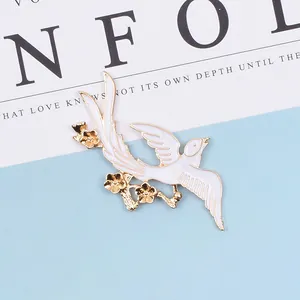 Macro detail of bird alloy brooch with white enamel oil drop and golden floral branch