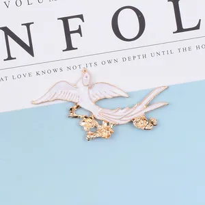 Detail of a white enamel bird brooch with golden flower branch for DIY hair accessories